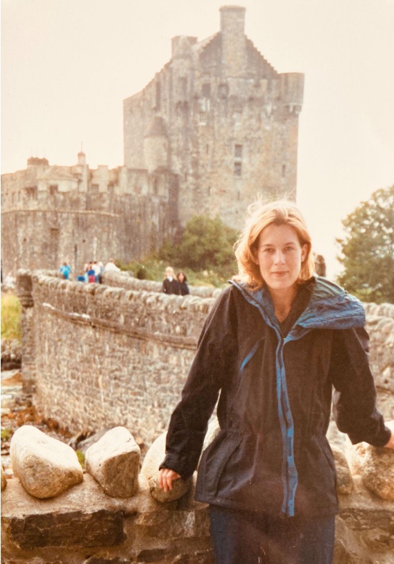 Abigail Morgan Prout leaning against a stone wall in front of a medieval castle