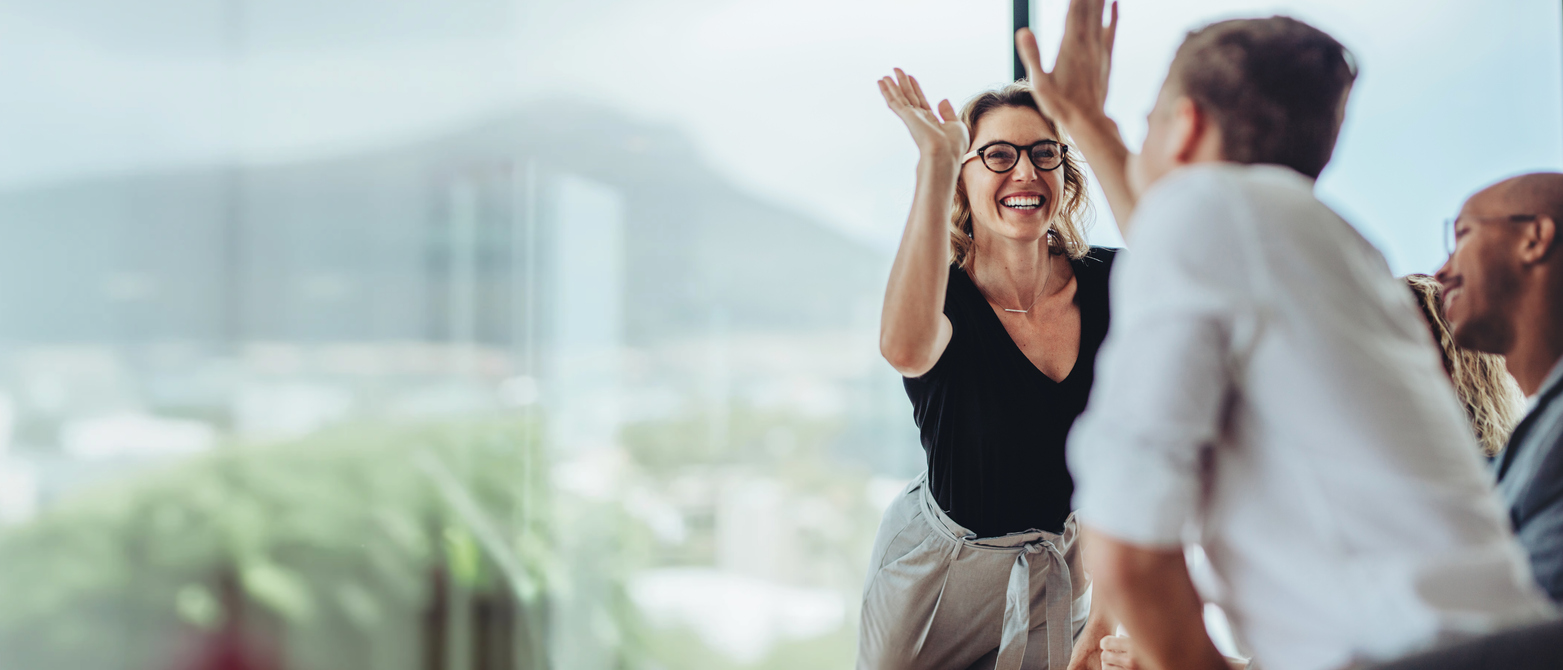 A woman high-fives a colleague, exemplifying the joy and confidence derived from a culture of empowerment and leadership success.