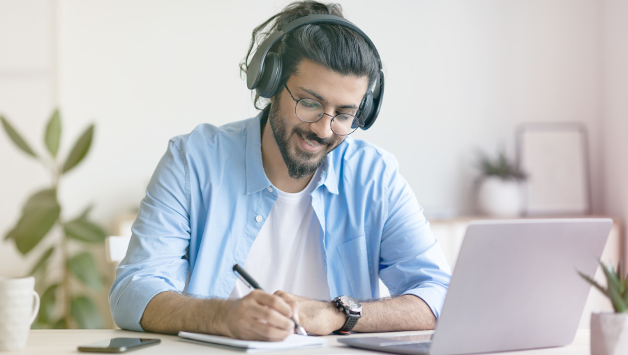 man smiling taking notes at computer