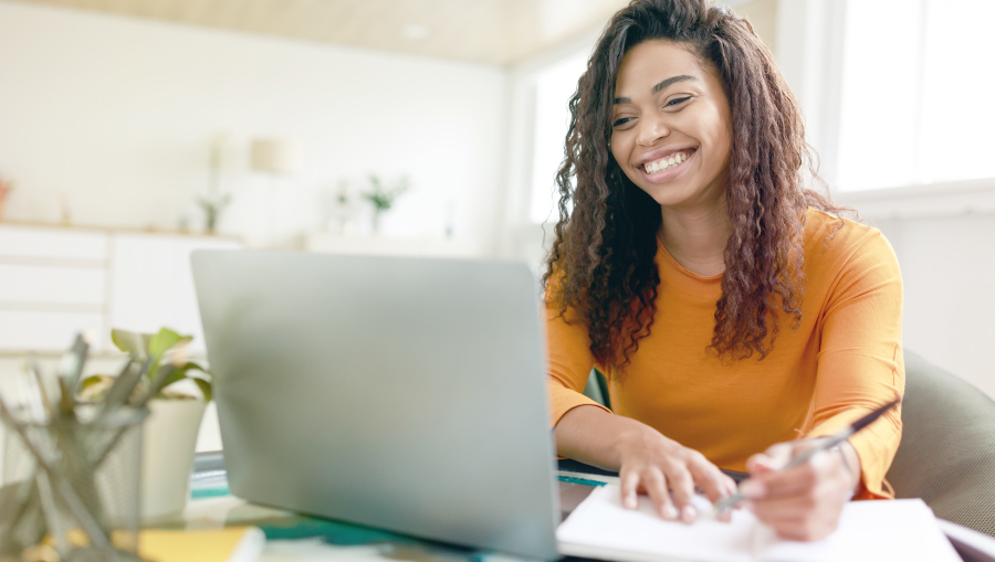 woman smiling taking notes at computer