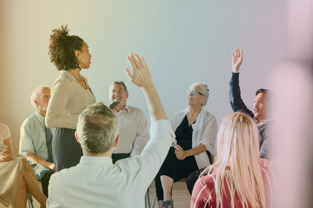 A woman stands in the middle of a circle of adults, facilitating a lively and productive conversation showing the impact of leadership development.