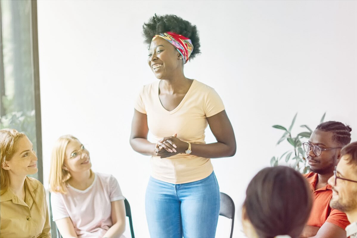 A woman confidently presents to a group of peers thanks to Co-Active coaching techniques.