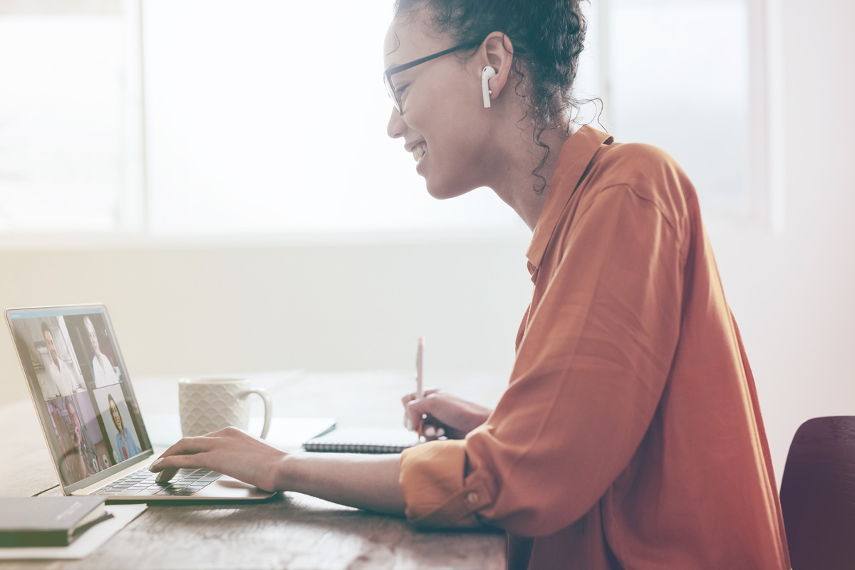 woman smiling looking at laptop while on conference call