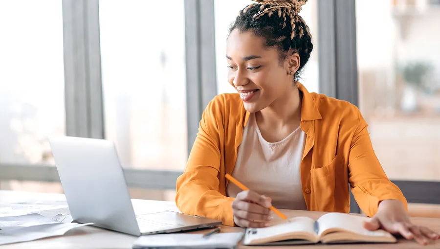woman taking notes watching laptop