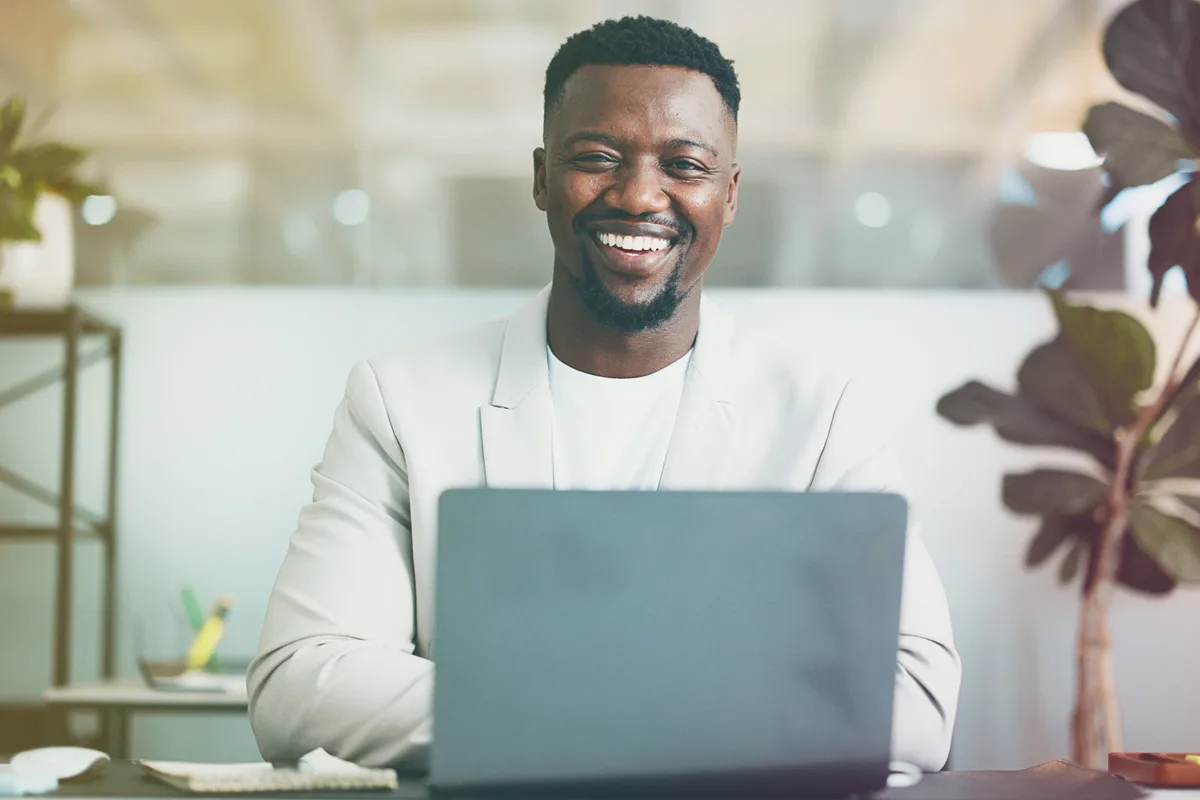 Professional smiling while working on laptop during virtual meeting