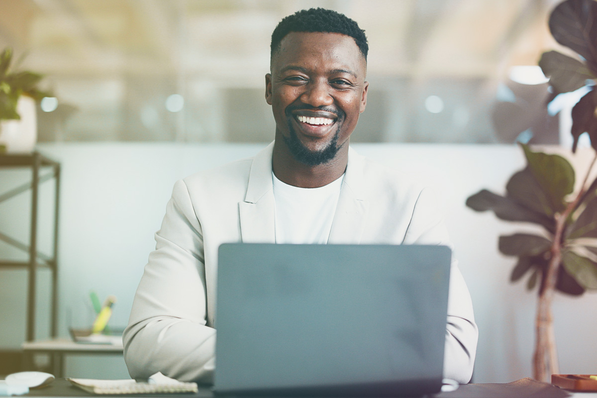 Professional smiling while working on laptop during virtual meeting