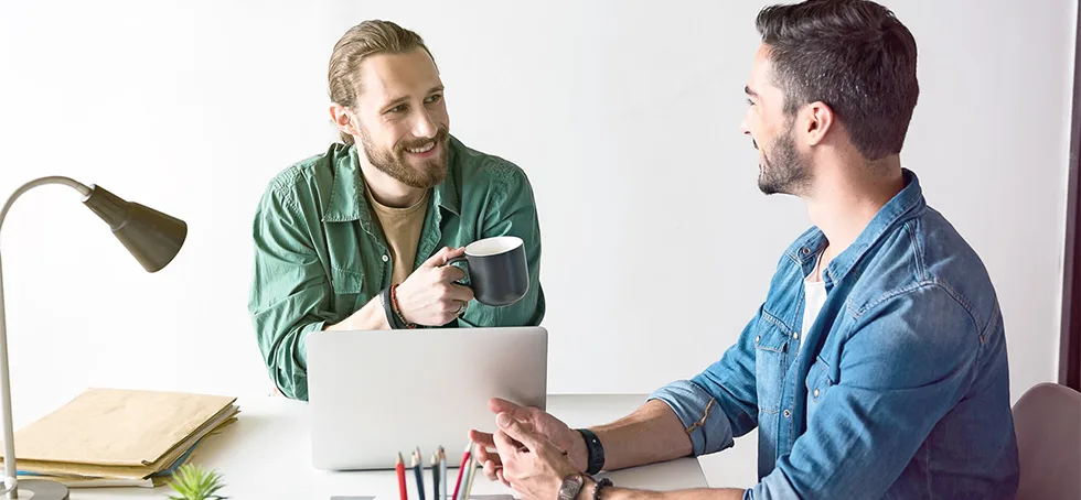 two men having conversation with laptop and coffee