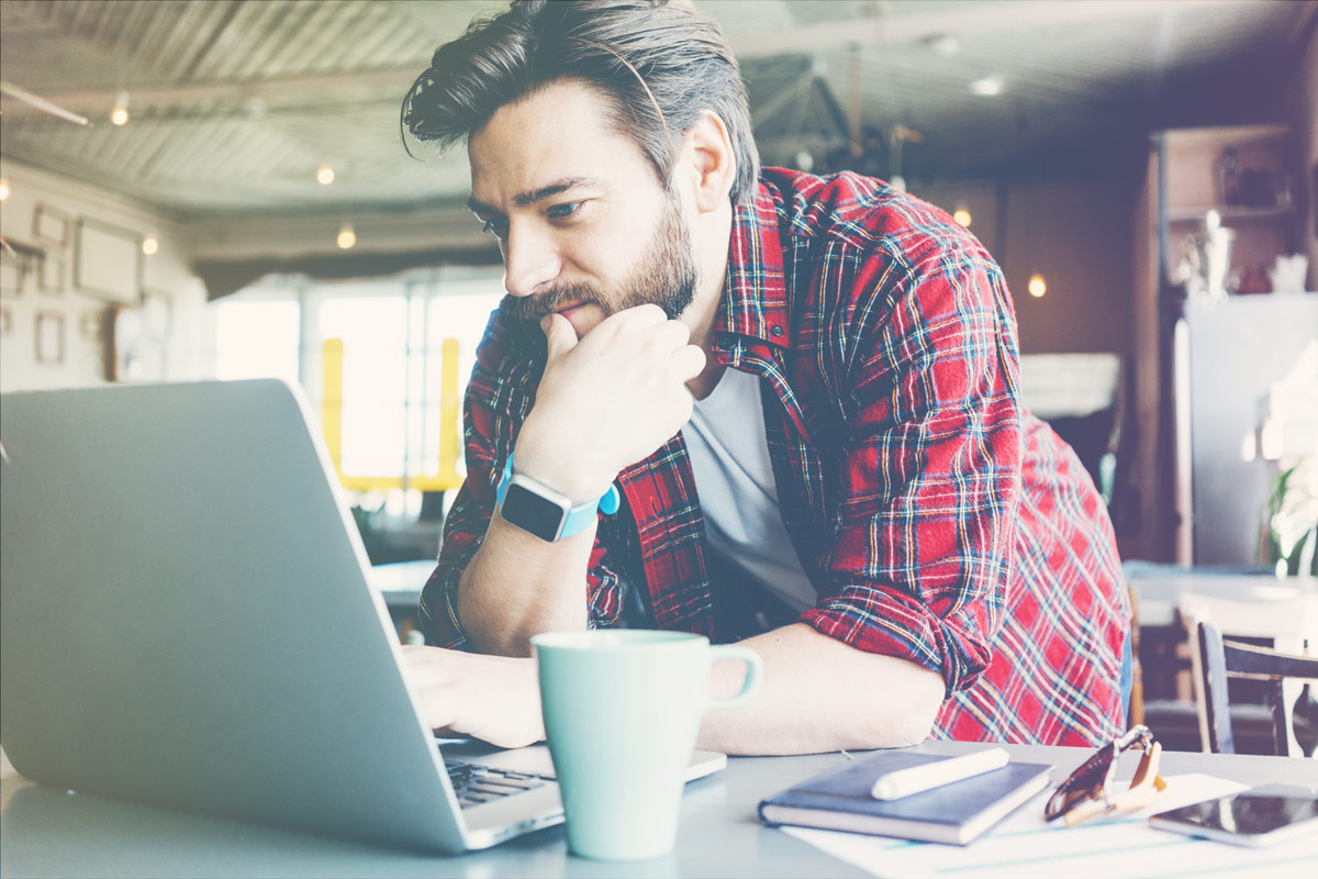 Professional reflecting while working on laptop in café
