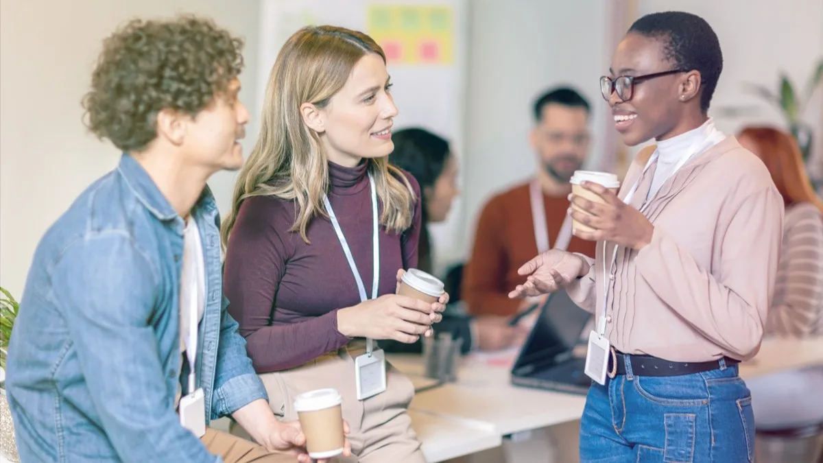 People discussing with coffee in their hands at an event.