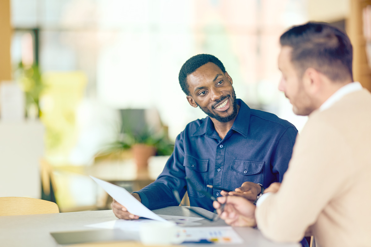 Two people talking over papers at a table