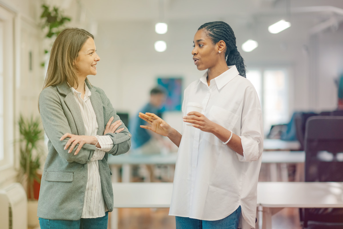Lady in white having a conversation with a lady in a grey coat