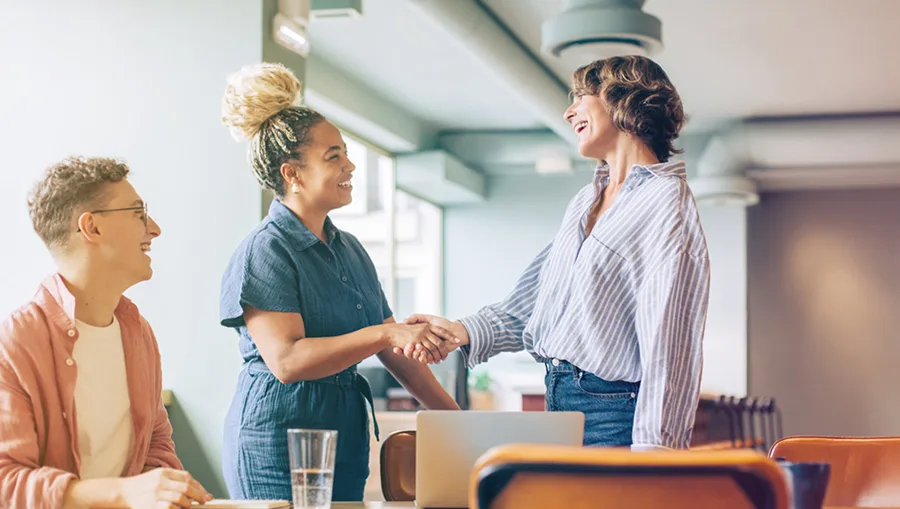 Women shaking hands at a co-working space.