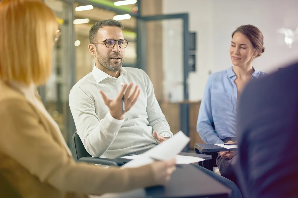 Man speaking during a group coaching or leadership discussion in an office setting