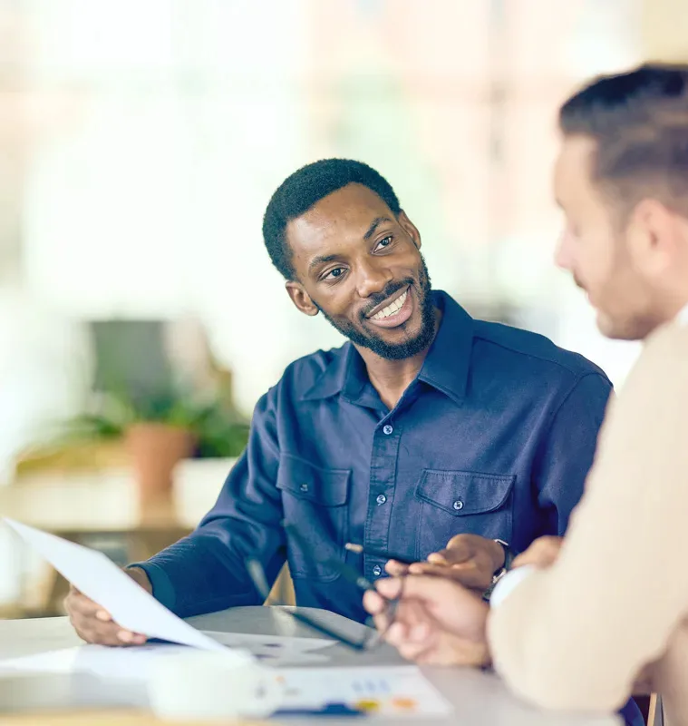 Men talking with paperwork in their hands.