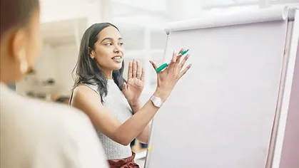 Woman presenting at a whiteboard.