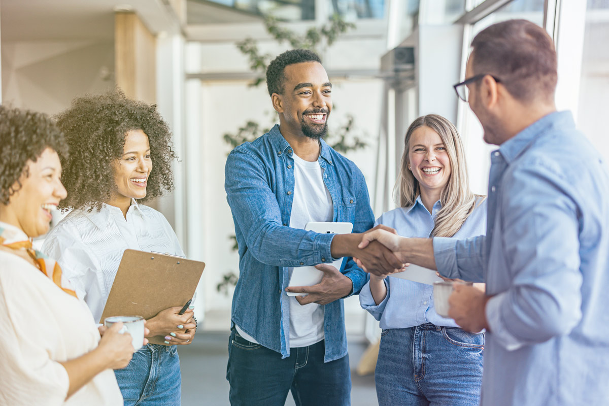 Team members shaking hands during a workplace leadership meeting.
