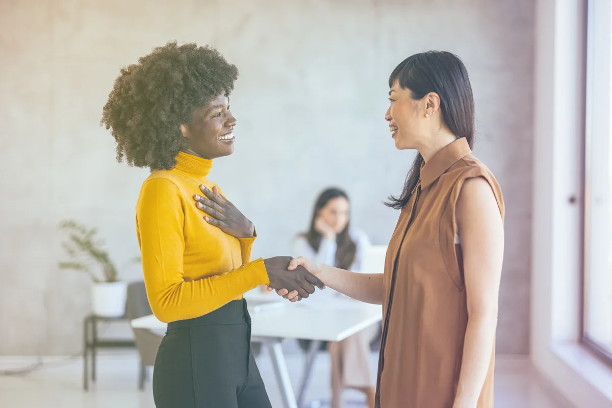 2026_02_CTI_Thought-Leadership-Article-3of4 (2) Two women smiling and shaking hands in a professional setting.