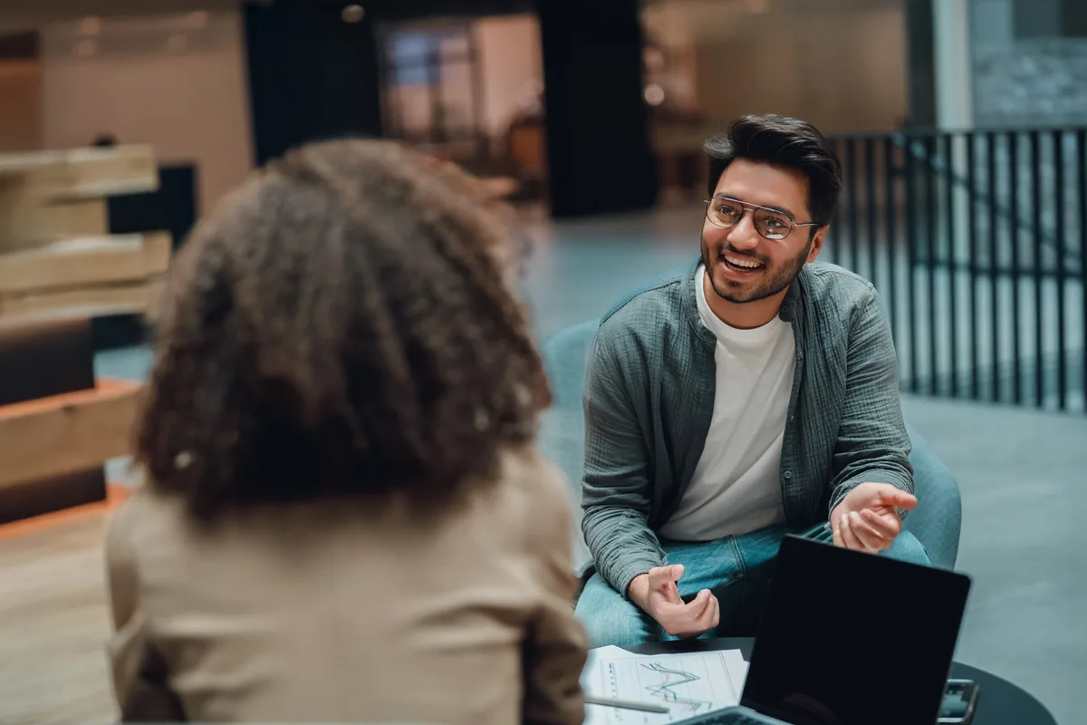 Two people talking during a coaching session with a laptop on the table.