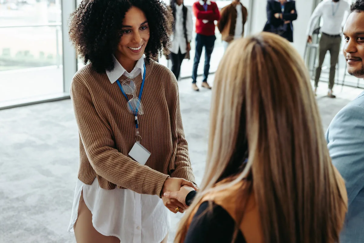 Two professionals shaking hands in an office lobby.