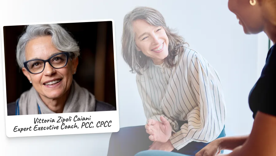 Two women talking at desk and taking notes.