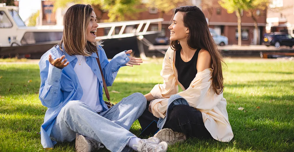 Two women laughing and chatting outdoors.