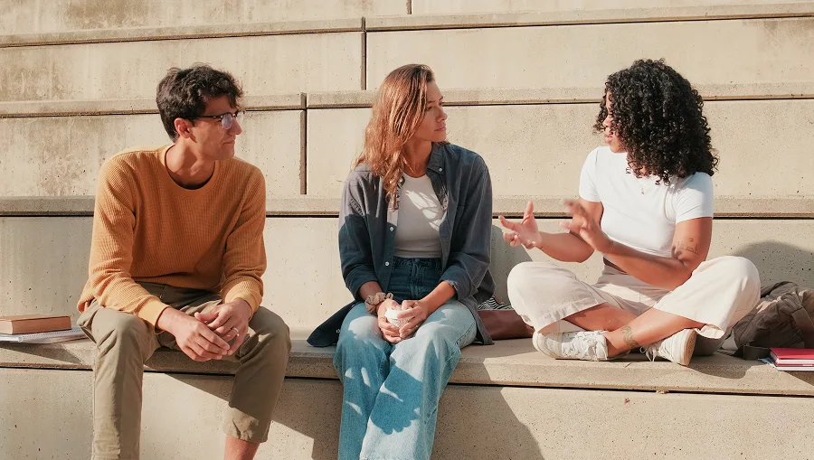 Three friends engaged in conversation outdoors.