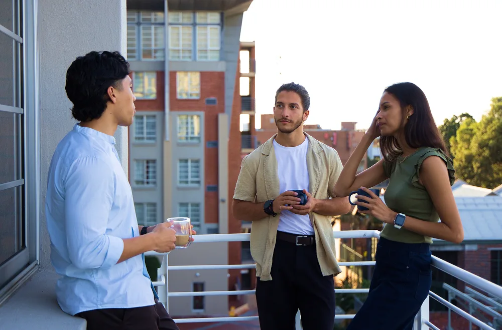 Three people chatting on a balcony.