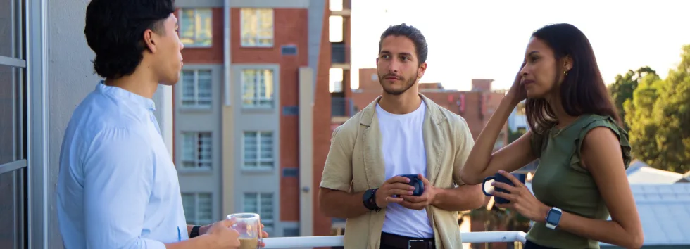 Three people chatting on a balcony.