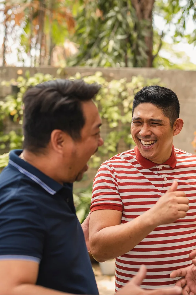 Three men laughing together outdoors.