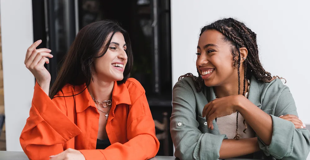 Two women smiling and chatting together.